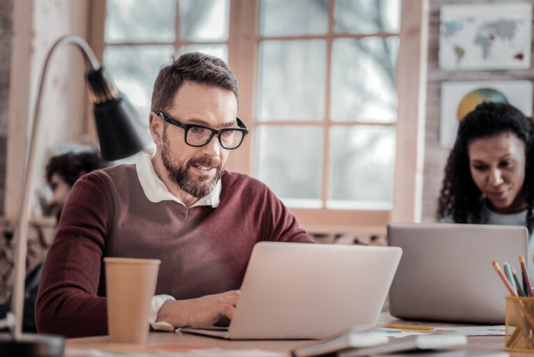 Positive delighted bearded man working at computer